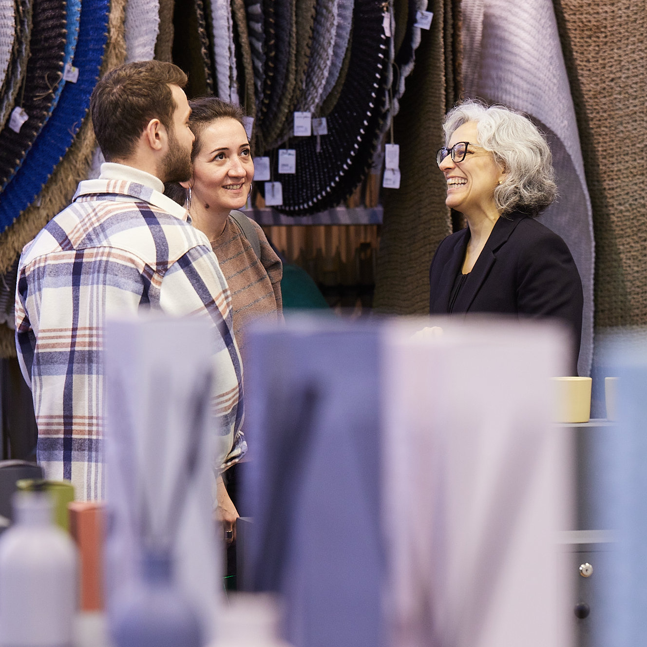 3 Personen an einem Messestand mit Düften und Teppiche auf der Ambiente