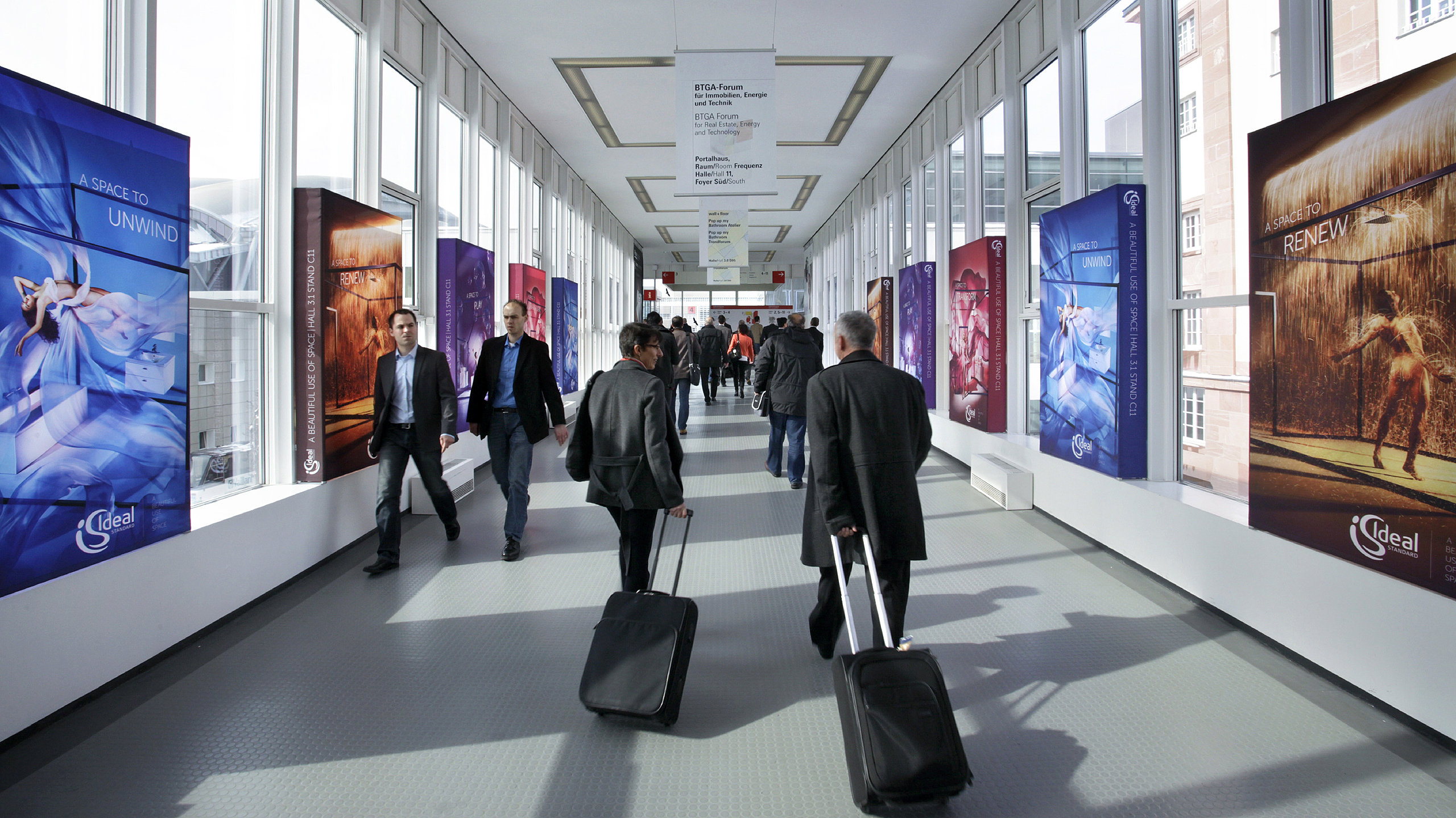 Trade fair visitors walk past advertising displays at Via Mobile